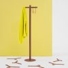 contemporary coat stand in brown finish in front of yellow wall