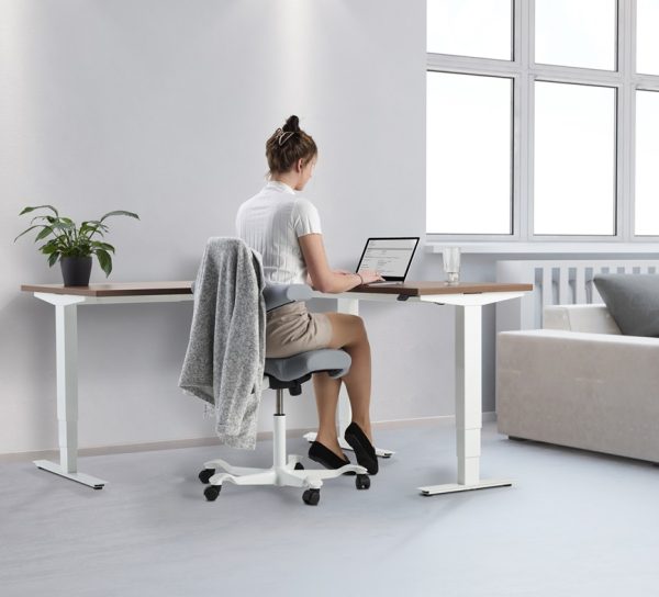 height adjustable desk with lady working. in reception roomset with sofa