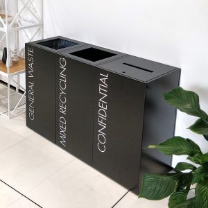row of black office recycling bins. i confidential with slot and lock and 2 standard with white lettering for waste streams