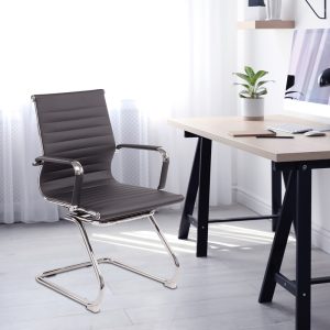 visitor chair grey leather and chrome frame in room shot by trestle style desk