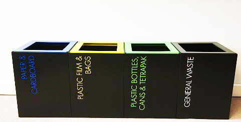 row of small black office recycling bins with lettering in different colours