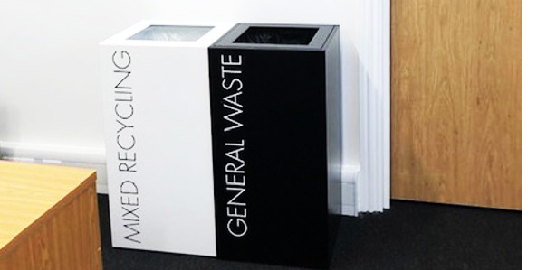 office recycling bins by office desk. One black with White lettering General Waste. One white with black lettering Mixed Recycling