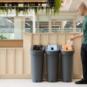 office recycling bin in row of three with marking for waste stream. in restaurant room shot