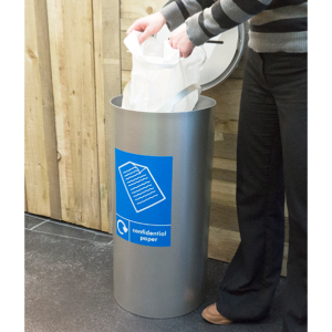 someone emptying a silver office recycling bin with blue Confidential Paper sticker